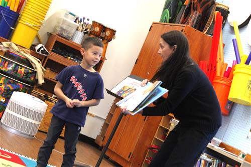 Woman holds up book for child to look at 