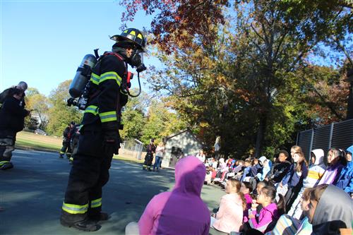 Fire Fighter in full gear speaks with children